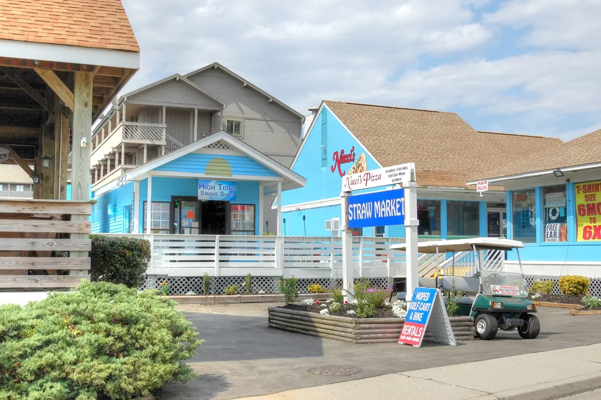 This image displays a lively streetscape with colorful storefronts and a golf cart parked nearby. The friendly, casual vibe highlights opportunities for shopping, dining, and exploring local businesses just a short trip from the property.